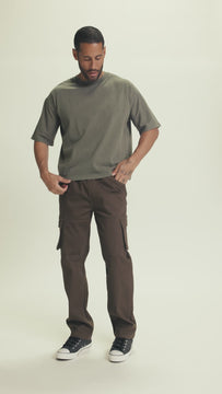 Video of model walking in HETFIELD relaxed fit dark olive cargo pants with pull-on waistband and side pockets, showcasing movement and streetwear styling.